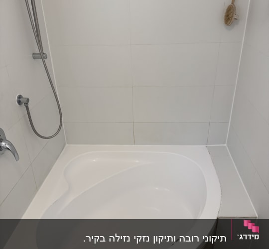 אמבטיה עם מקלחת יד ומברשת תלויה על הקיר